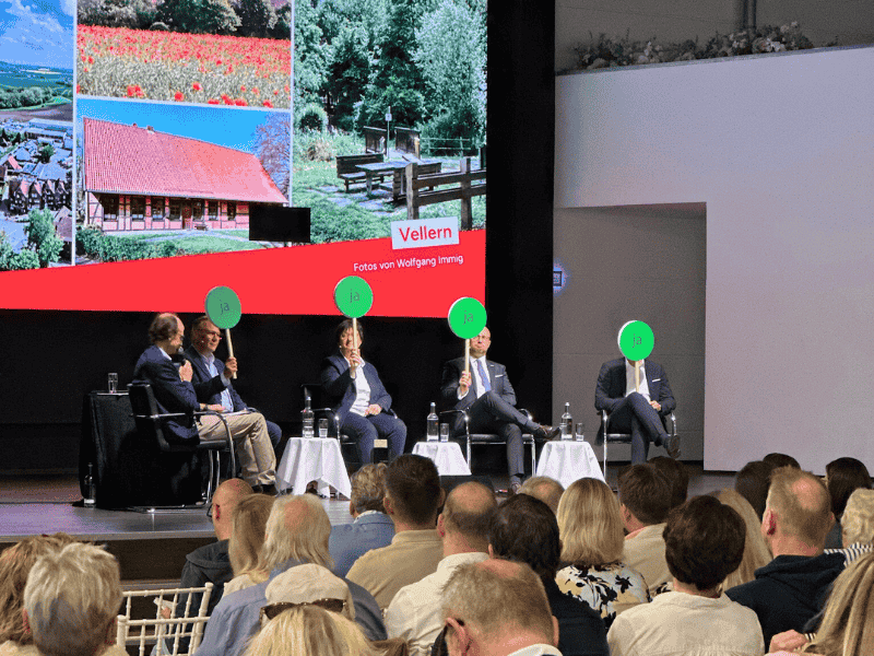 Bürgermeisterwahl Beckum 2025 – Abstimmung im Eventcenter Kandidat:innen der Bürgermeisterwahl 2025 in Beckum bei einer Publikumsdiskussion im Eventcenter – Abstimmung mit grünen Ja-Schildern.