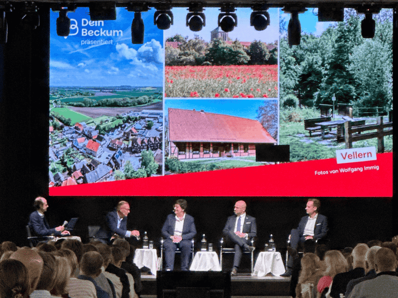 Bürgermeisterwahl Beckum 2025 – Podiumsdiskussion im Eventcenter Podiumsdiskussion zur Bürgermeisterwahl 2025 in Beckum mit Kandidat:innen auf der Bühne – Großbildschirm mit Landschaftsbildern aus Vellern.